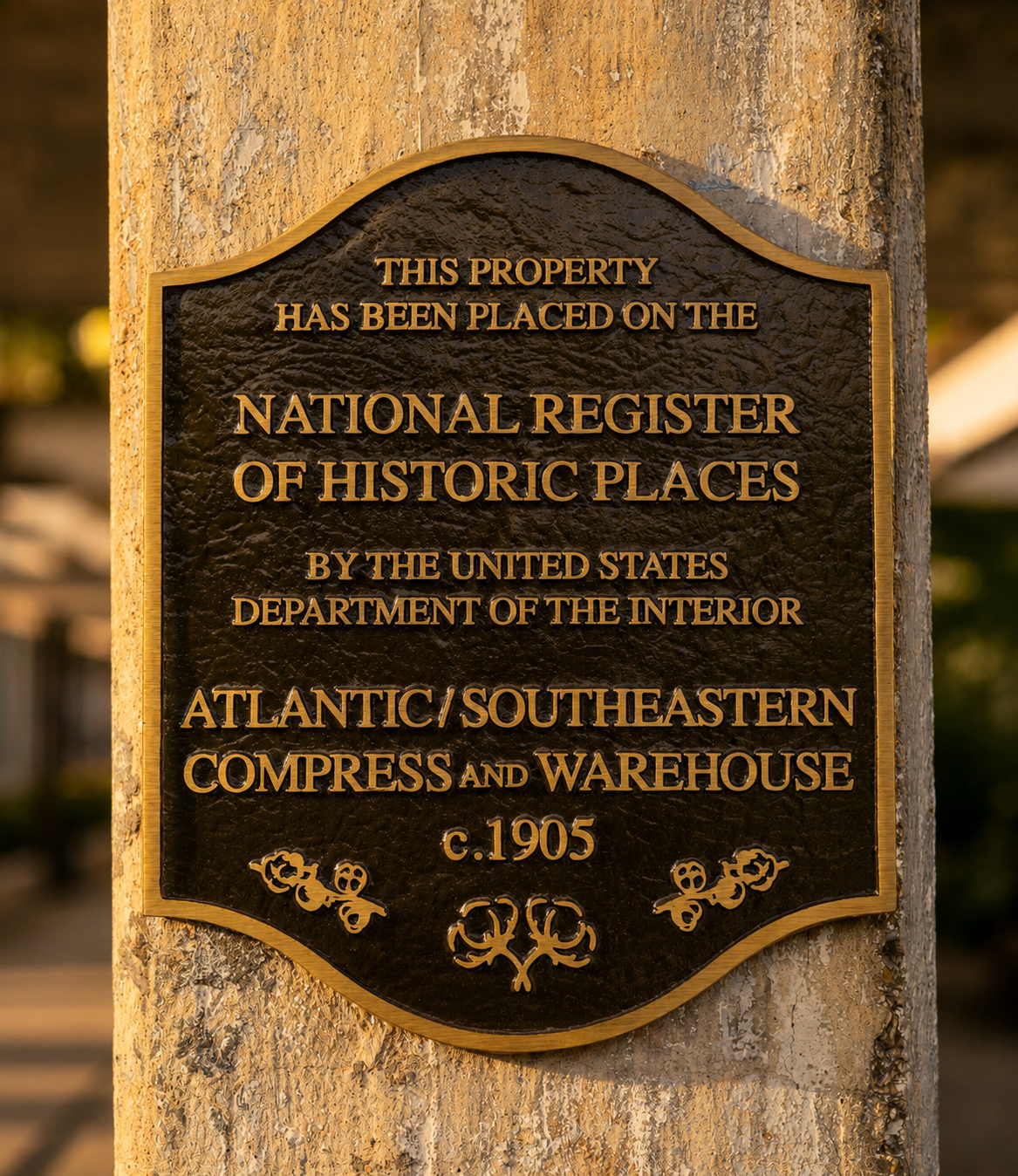 Bronze National Register of Historic Places plaque mounted on an original concrete column at Studioplex, reading Atlantic / Southeastern Compress and Warehouse, c.1905